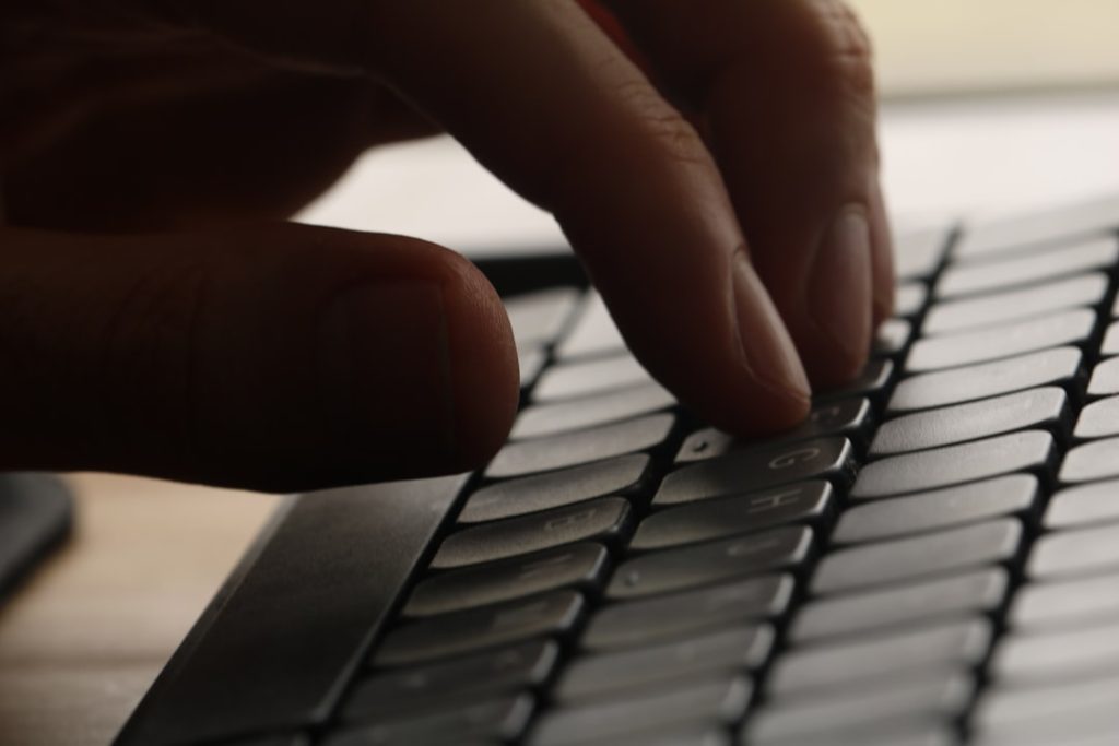 Close-up of a hand typing on a computer keyboard.